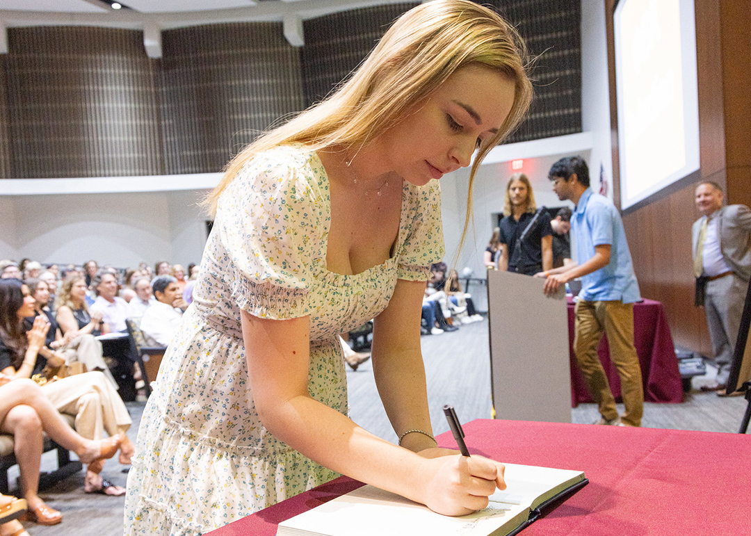 Phi Beta Kappa member writing in a book at a meeting