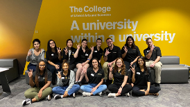 Group of students wearing the same black College Ambassadors t-shirt and posing with the ASU fork hand sign